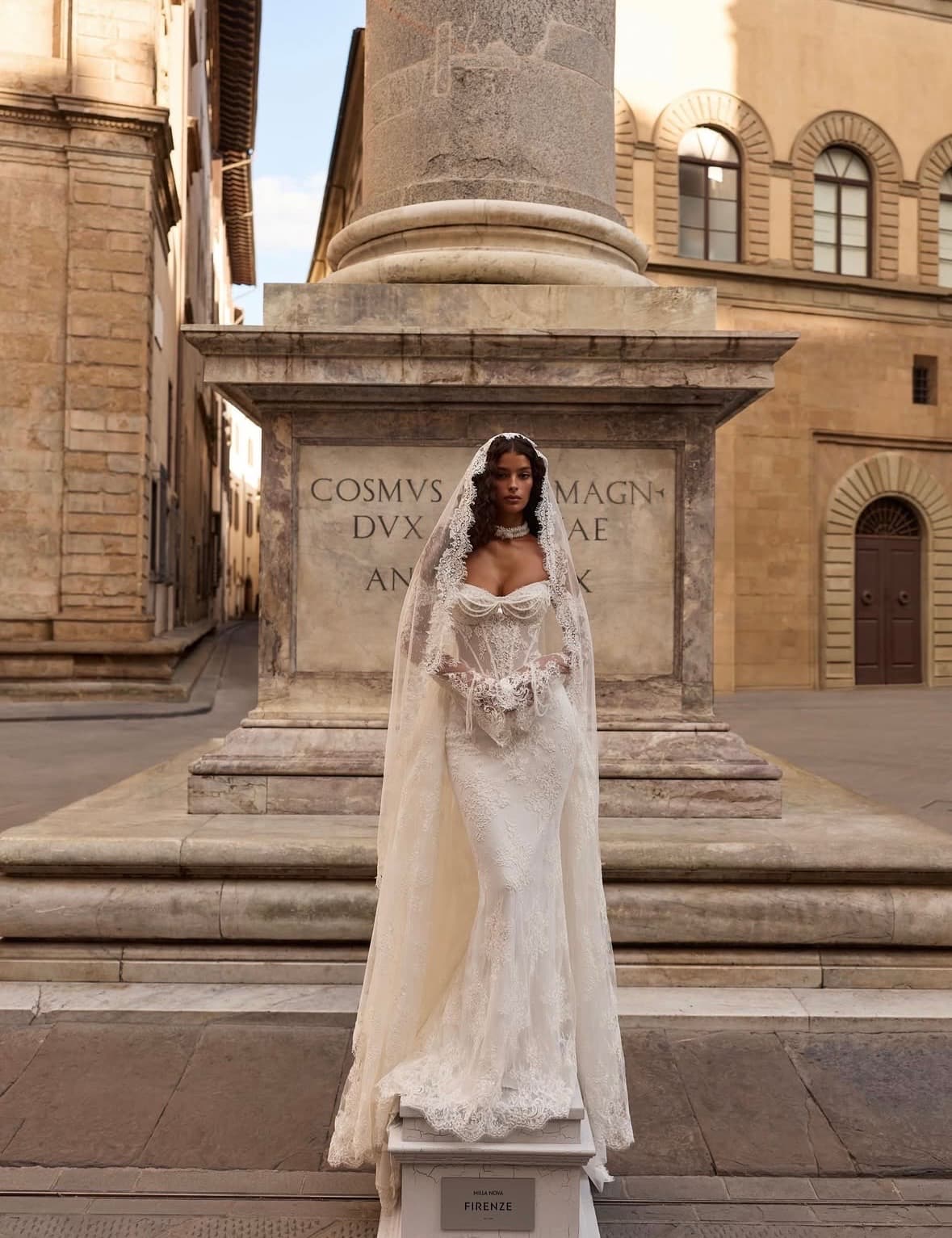 Bride in a lace corset gown and mantilla veil on a stone piazza